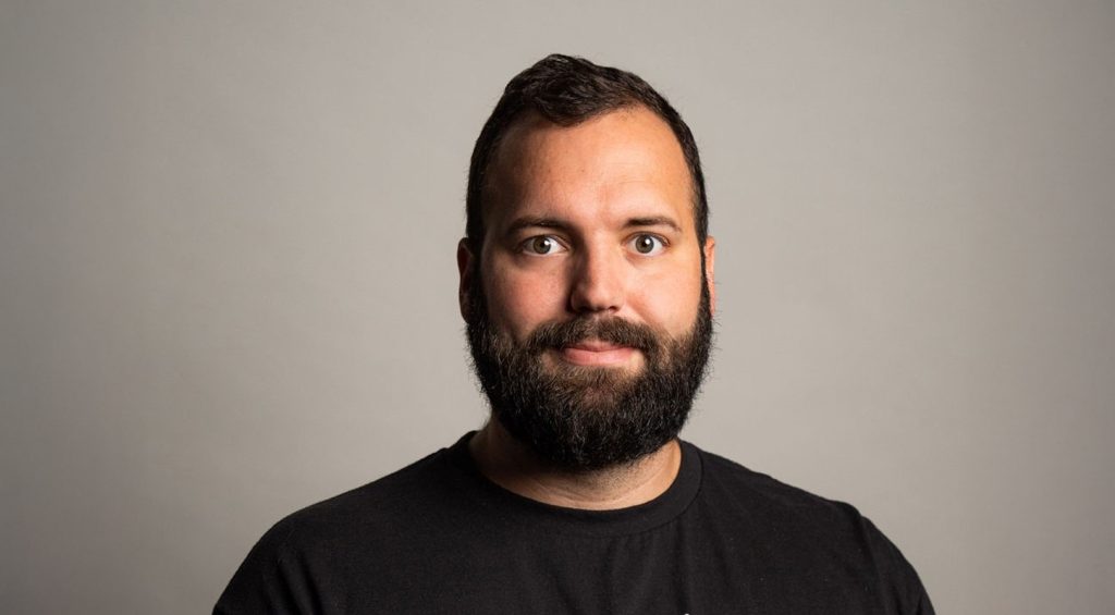 Cleary team member, Zach Minnier head and shoulders portrait wearing a black tshirt standing in front of a gray background
