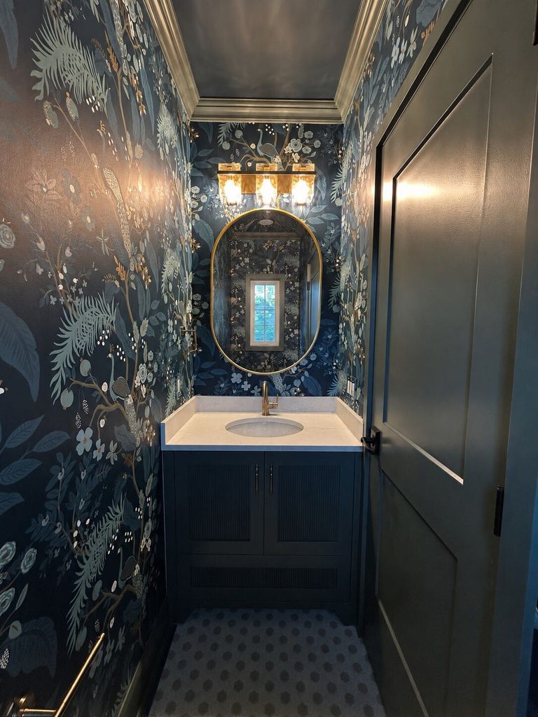 Dark green powder room in Clintonville with brass and crystal wall sconces, layered trim, and a rich, moody color palette.